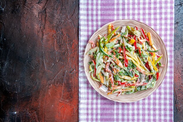 Vista dall'alto insalata di verdure sul piatto sulla tovaglia sul posto di copia tavolo rosso scuro