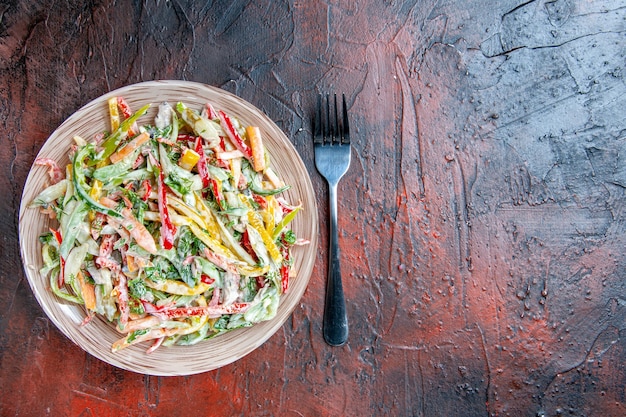 Vista dall'alto insalata di verdure sulla forcella del piatto sul posto libero tavolo rosso scuro