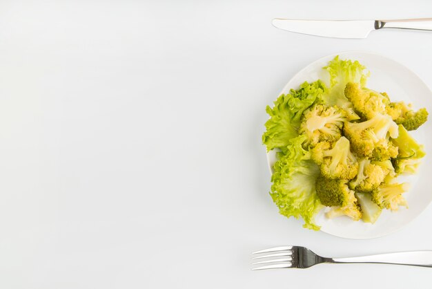 Vista dall'alto insalata verde con posate e copia-spazio