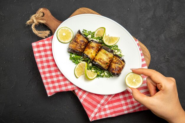 Vista dall'alto involtini salati di melanzane piatto cucinato con fette di limone su tavola scura cena olio cucina pasto piatto di agrumi