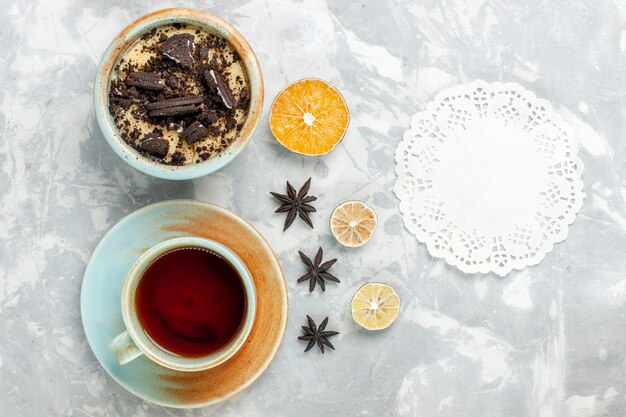 Vista dall'alto la tazza di tè con il dessert del biscotto sulla torta di cioccolato bianca chiara del biscotto dello scrittorio cuocere lo zucchero della torta dolce