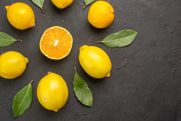 Vista dall'alto limoni freschi e aspri allineati sul tavolo scuro, agrumi giallo lime