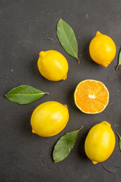 Vista dall'alto limoni freschi e aspri allineati sul tavolo scuro, agrumi giallo lime