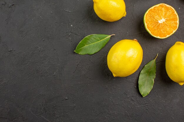 Vista dall'alto limoni freschi e aspri allineati sul tavolo scuro, agrumi giallo lime