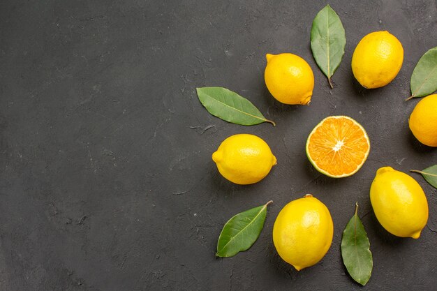 Vista dall'alto limoni freschi e aspri foderati sul pavimento scuro agrumi giallo lime frutta