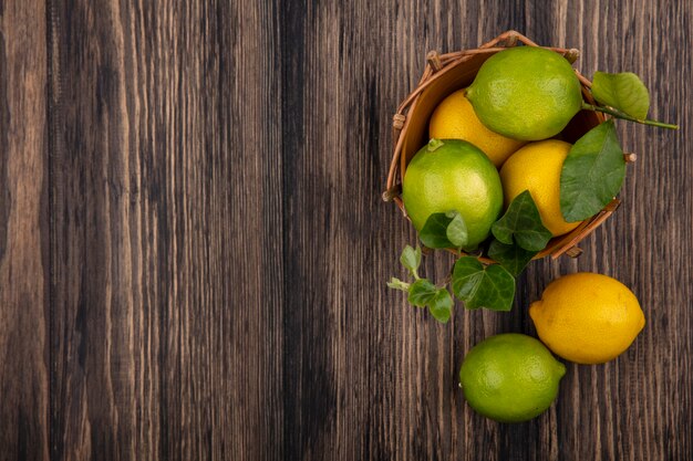 Vista dall'alto lo spazio della copia limette con limoni in un cesto su sfondo di legno