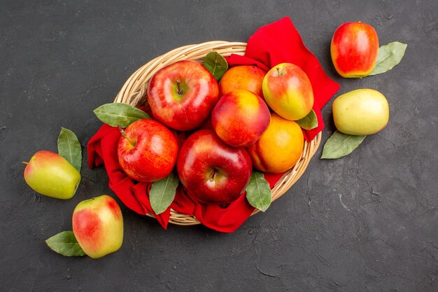 Vista dall'alto mele fresche con pesche all'interno del cesto su tavola scura frutta matura albero fresco