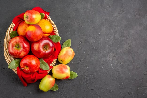 Vista dall'alto mele fresche con pesche all'interno del cesto su un albero da frutto da tavola scuro fresco maturo