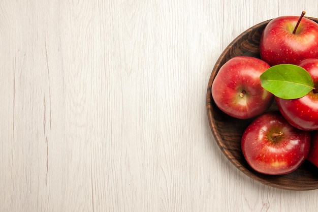 Vista dall'alto mele rosse fresche frutti maturi e morbidi sul pavimento bianco frutta albero di colore rosso pianta fresca