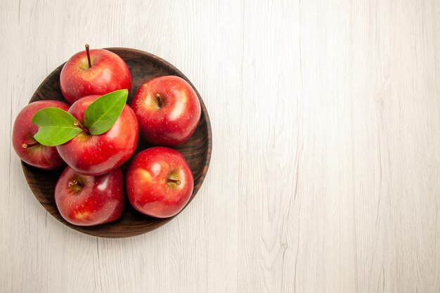 Vista dall'alto mele rosse fresche frutti maturi e morbidi sulla pianta fresca dell'albero di colore rosso della frutta della scrivania bianca
