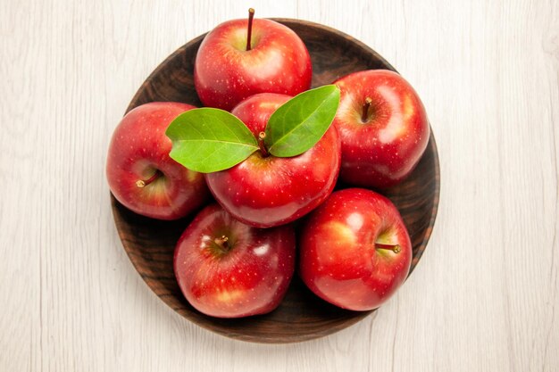 Vista dall'alto mele rosse fresche frutti maturi e morbidi sulla pianta fresca dell'albero di colore rosso della frutta della scrivania bianca