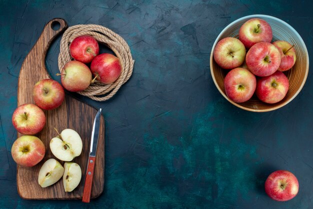 Vista dall'alto mele rosse fresche succose e pastose con scrivania marrone su sfondo blu scuro frutta matura fresca vitamina mellow