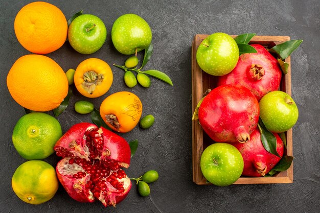 Vista dall'alto melograni freschi con mele e altri frutti sul colore della frutta matura superficie scura