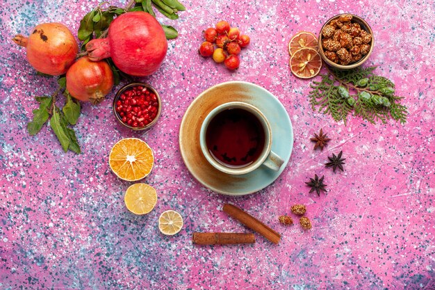 Vista dall'alto melograno fresco con cannella e tazza di tè sulla superficie rosa