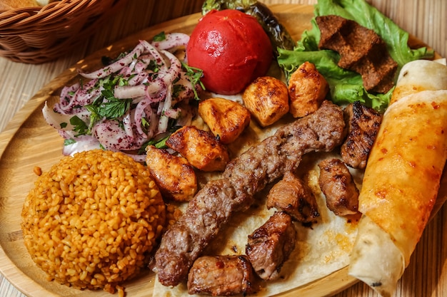 Vista dall'alto mix di kebab con cipolla di bulgur e pane pita con verdure su un supporto