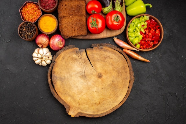 Vista dall'alto pagnotte di pane scuro con condimenti e verdure su fondo scuro piatto salutare per insalata