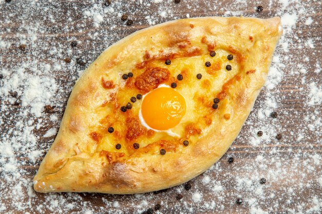 Vista dall'alto pane cotto con uova cotte e farina sulla pasta scrivania marrone cuocere il panino del pane delle uova