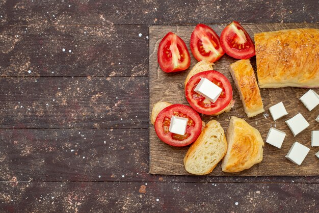 Vista dall'alto pane gustoso fresco lungo panino formato pasta tagliata con formaggio e pomodori sulla farina di pane di pasta sfoglia di legno marrone scrivania