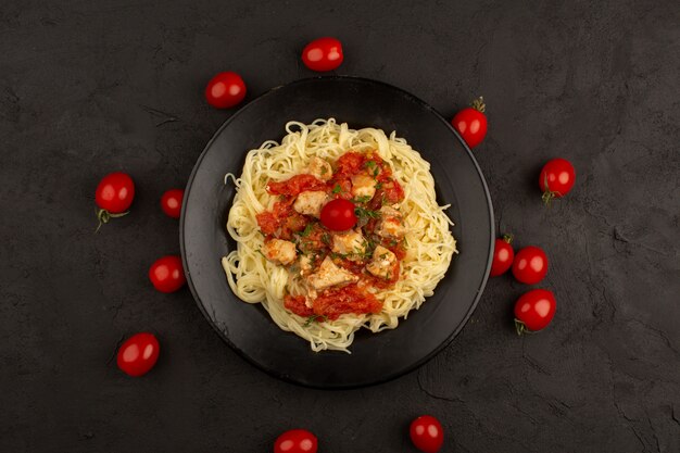 vista dall'alto pasta cotta con ali di pollo e salsa di pomodoro all'interno della banda nera sul buio