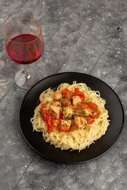 vista dall'alto pasta cotta con ali di pollo e salsa di pomodoro all'interno della banda nera sul grigio