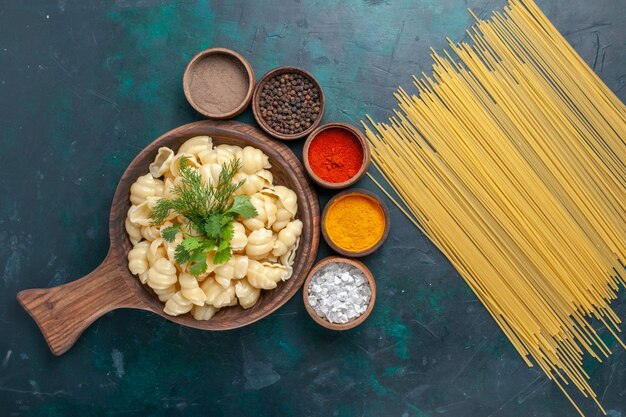 Vista dall'alto pasta cotta con diversi condimenti sulla scrivania scura