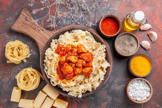 Vista dall'alto pasta cotta con pollo e condimenti su una superficie scura pasta piatto pasta scura