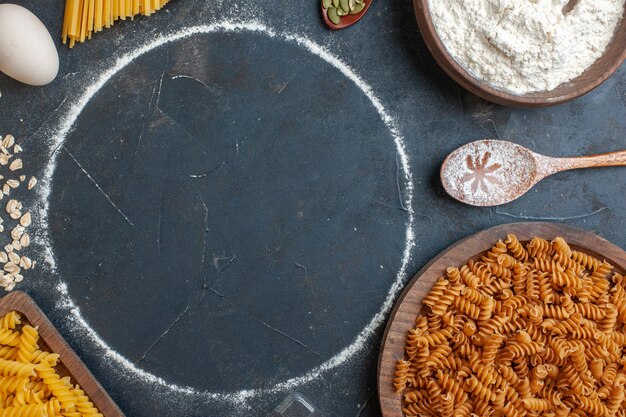 Vista dall'alto pasta cruda con cereali e uova su uno sfondo grigio scuro pasta alimentare colore cottura cucina pasto oscurità