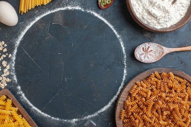 Vista dall'alto pasta cruda con cereali e uova su uno sfondo grigio scuro pasta alimentare colore cottura cucina pasto oscurità