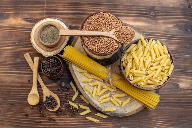 Vista dall'alto pasta cruda con grano saraceno e condimenti sulla superficie marrone