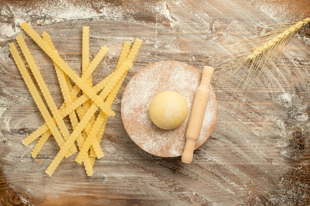 Vista dall'alto pasta di pasta cruda con farina su sfondo marrone in legno pasta pasta cruda cibo pasta