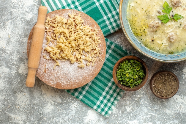 Vista dall'alto pasta e mattarello su tavola di pasta su tovaglia su sfondo grigio