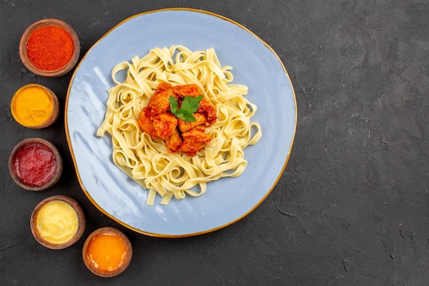 Vista dall'alto pasta e salse sugo di pasta e carne appetitosa su un piatto e sei tipi di salse colorate diverse sul tavolo