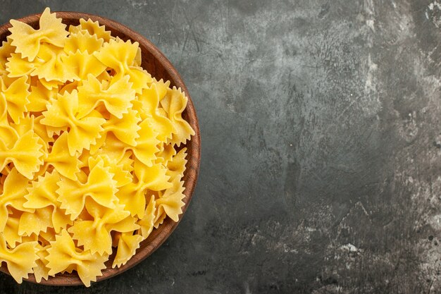 Vista dall'alto pasta italiana cruda all'interno del piatto su sfondo grigio scuro