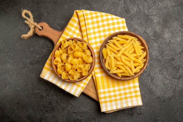 Vista dall'alto pasta italiana cruda all'interno di piatti marroni sul grigio