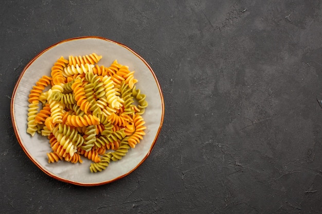 Vista dall'alto pasta italiana cucinata pasta a spirale insolita all'interno del piatto nello spazio buio