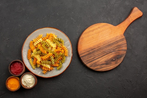 Vista dall'alto pasta italiana cucinata pasta a spirale insolita con condimenti sullo spazio buio