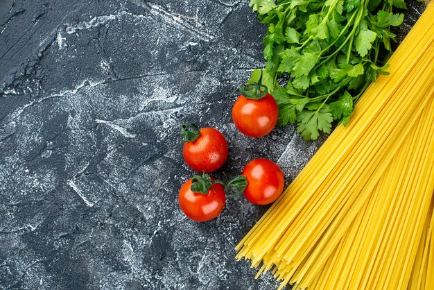 Vista dall'alto pasta lunga cruda con verdure e pomodori su sfondo grigio colore cucina pasta pasta cibo cucina cucina