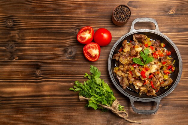 Vista dall'alto pasto di verdure cotte con carne e verdure sullo scrittorio di legno marrone