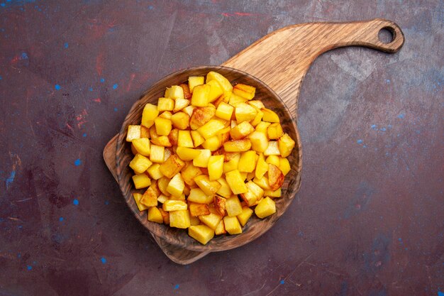 Vista dall'alto patate cotte a fette all'interno del piatto su viola scuro