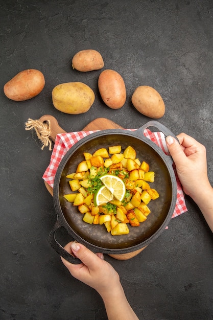 Vista dall'alto patate fritte all'interno della padella con patate fresche su sfondo scuro