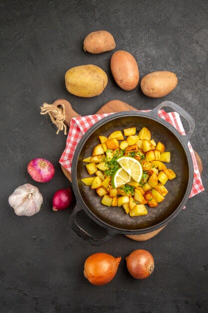 Vista dall'alto patate fritte all'interno della padella con verdure fresche su sfondo scuro