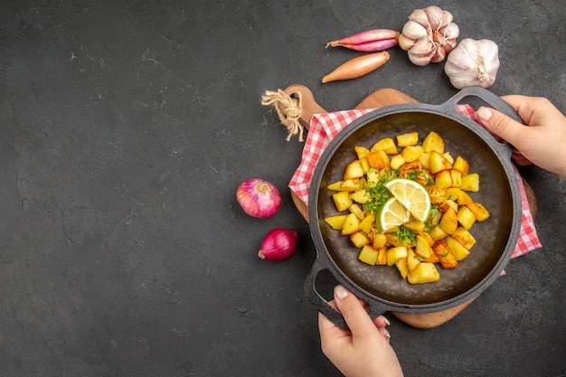 Vista dall'alto patate fritte all'interno di una padella con limone sullo sfondo scuro