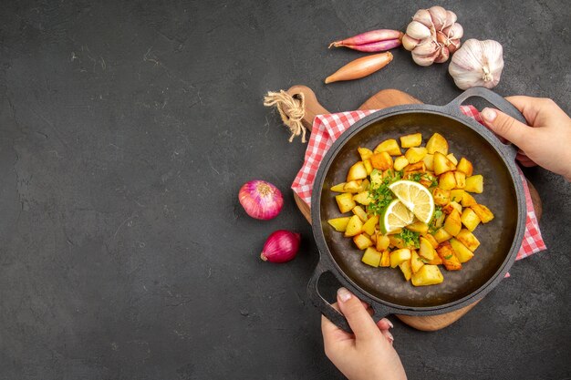 Vista dall'alto patate fritte all'interno di una padella con limone sullo sfondo scuro