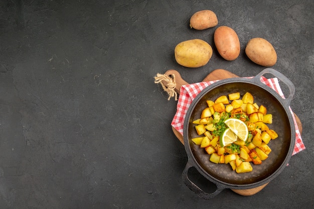 Vista dall'alto patate fritte all'interno di una padella con limone sullo sfondo scuro