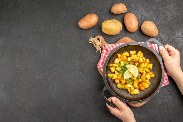Vista dall'alto patate fritte all'interno di una padella con limone sullo sfondo scuro