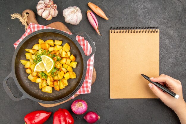 Vista dall'alto patate fritte all'interno di una padella con verdure sullo sfondo scuro