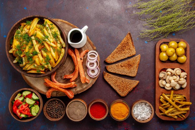 Vista dall'alto patate fritte con condimenti pane e verdure diverse sulla superficie scura