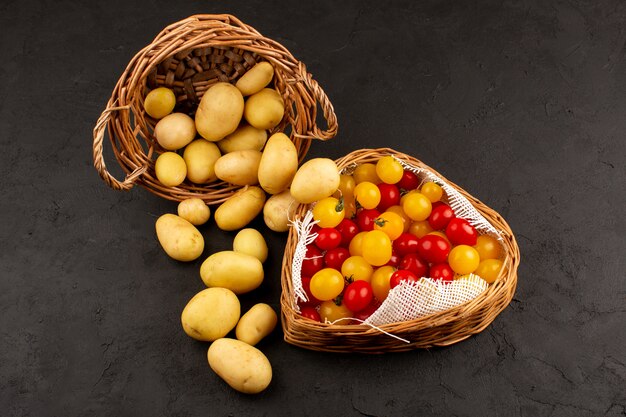 vista dall'alto patate insieme a pomodori rossi e gialli all'interno dei cestini sulla scrivania grigia