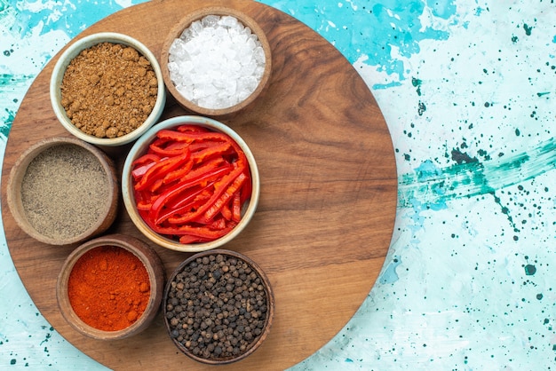Vista dall'alto peperone rosso a fette con sale pepe e condimenti diversi sullo sfondo azzurro foto a colori del prodotto sale pepe