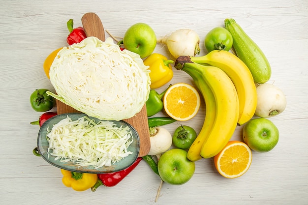 Vista dall'alto peperoni freschi con banane cavoli e mele su sfondo bianco foto insalata vita sana dieta colore maturo